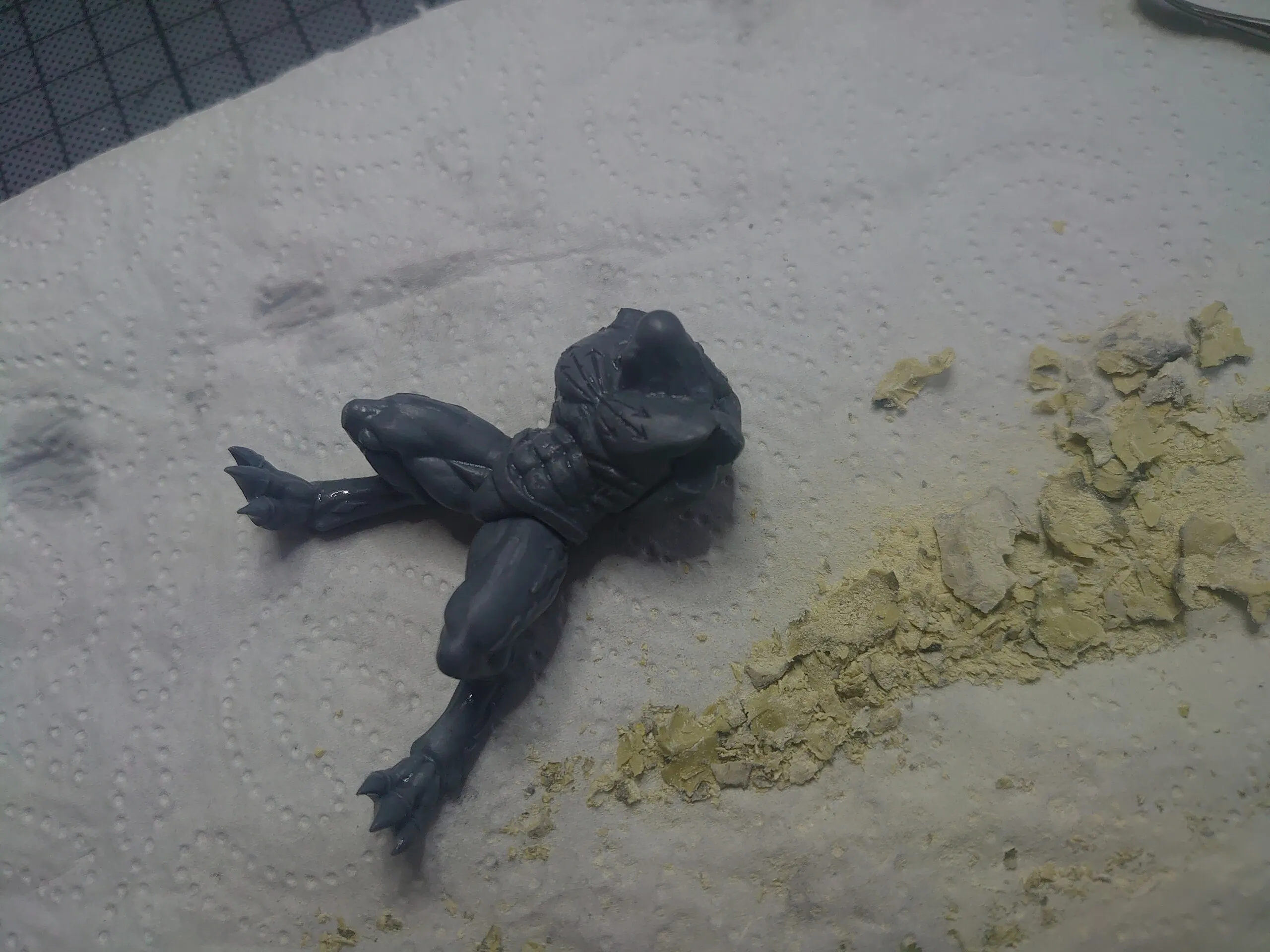 Liegende dunkle Figur neben Sand und Streumaterial